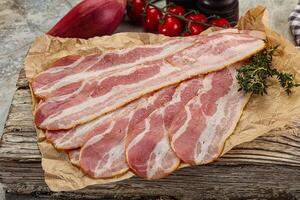 Sliced pork bacon over board photo