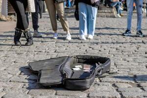 Istanbul, Turkey - December 29, 2022. Open guitar case on the street for donations with blurred people in the background. photo