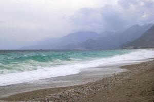 Beautiful stormy sea with dark cloudy sky and mountains on background. Antalya, Turkey. photo