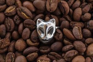 Top view on silver ring on a background of coffee beans. Handcraft precious item. Jewelry accessories. photo
