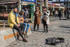 Istanbul, Turkey - December 29, 2022. Street Musician Playing Guitar for Tourists on a Cobblestone Street. photo