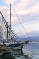 fethiye, Turquía - diciembre 8, 2022. lujoso yates amarrado en un tranquilo mar puerto a puesta de sol en un antecedentes de montañas. foto