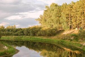 Beautiful lake surrounded by green forest and blue sky with white clouds landscape background. photo