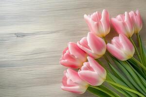 A bouquet of pink tulips is arranged on a wooden table photo