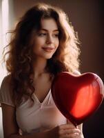 Portrait of young woman with wavy hair smiling gently while holding a red heart-shaped balloon in Valentines Day photo