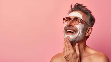 Joyful portrait of a man applying facial cream with a delighted expression. Cosmetic advertisement photo