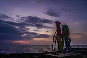 Close-up view of the word LOVE placed on the coastline against a sunset sky with empty space for photocopying. photo