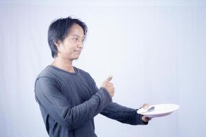 close up view of handsome asian man holding plate with happy expression, showing that the food is delicious on isolated white background for advertising. photo