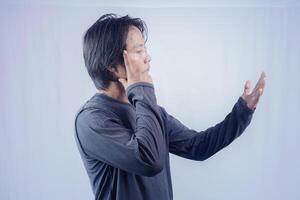 asian man is thinking about something with a look towards palm, isolated on white background for copy space. photo