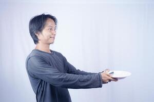 close up view of handsome asian man holding plate with happy expression, showing that the food is delicious on isolated white background for advertising. photo