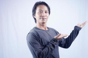 Handsome Asian man facing the camera is pointing at the copy space for advertising on an isolated white background. photo