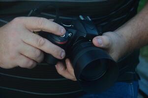 un profesional fotógrafo sostiene un cámara en su manos y ajusta eso antes de tiroteo. foto