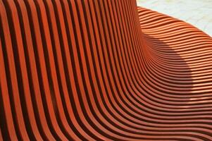 Brown wooden curved slats. Bench element, architectural design of building exterior. Abstract background. photo