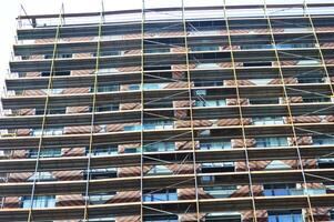 Modern high-rise residential building under construction with scaffolding and decorative safety net. photo