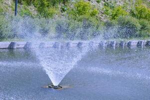 A soft stream of water flows like a funnel from the fountain. Beautiful splashes of water on a sunny summer day. photo