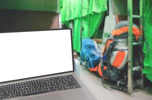 cerca arriba de moderno ordenador portátil con borroso antecedentes de mochilas en pasillo dentro de durmiente tren cabina a noche, blanco pantalla con recorte camino foto