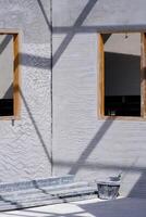 Perspective view of wooden window frames on concrete wall with many carbon steel rectangular tubes and work tools inside of house construction site in vertical frame photo