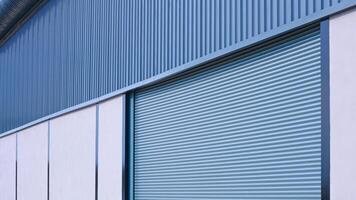 Automatic roller shutter entrance door on gray concrete and corrugated metal wall of new modern warehouse building, Perspective side view photo