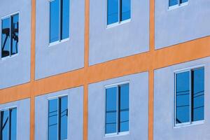 Low angle and side view of blue sky reflection on glass windows surface of modern building wall photo