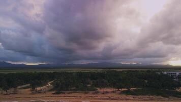 Flight over the ocean coast, green jungles, and fields against the backdrop of a softly pink-purple sunset behind the mountains of the Dominican Republic. Gentle tropics video