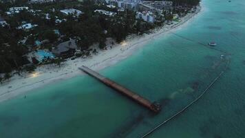 un aereo cinematico Visualizza cattura un' molo con un' gazebo a crepuscolo, incorniciato di il vivace turchese acque di il oceano nel il sfondo. adatto per aggiungendo testo. dominicano, degno di nota punta cana video