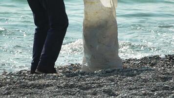 basura en playa - mayor hombre recoge basura en playa después tormenta, mantener limpieza y conservación ambiente. video