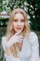 A blonde girl with long hair on a walk in a spring park. Springtime and blooming apple trees. photo