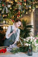 A woman in her florist shop collects bouquets of flowers. The concept of a small business. Bouquets of tulips for the holiday on March 8. photo