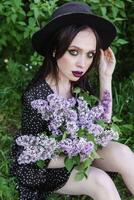 un de moda niña con oscuro cabello, un primavera retrato en lila tonos en verano. brillante profesional constituir. foto