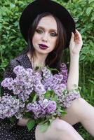 un de moda niña con oscuro cabello, un primavera retrato en lila tonos en verano. brillante profesional constituir. foto