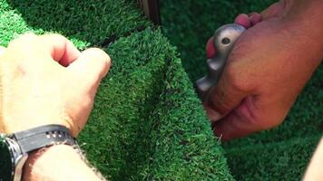 Man Cuting Artificial Grass carpet with knife. Artificial turf. Close up on hands. video