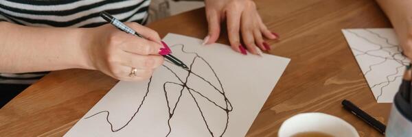 TVER, RUSSIA - FEBRUARY 25, 2023. Woman draws neurographics at table at a psychological session, neurographic pencil drawing to remove restrictions, art therapy photo