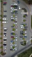 Busy large modern carpark with symmetrical roads rows of parking bays lots of symmetry and colours aerial view from drone up above looking down. video