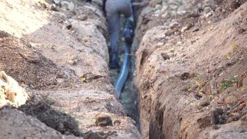 Plastic pipes laid in trenches. Workers are installing water pipeline under a city street in a trench. New pipeline in a process of building, under construction. Workers are laying pipeline. Close up video