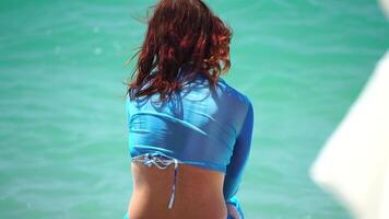 donna andando nel mare su spiaggia a tramonto durante estate vacanza vacanze rallentatore, avvicinamento, indietro Visualizza. peso perdita e corpo Immagine concetto. irriconoscibile donna con Perfetto in forma corpo gode mare spiaggia video