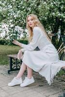 A blonde girl with long hair on a walk in a spring park. Springtime and blooming apple trees. photo