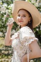 An attractive long-haired woman walks in the spring in the park of blooming apple trees. photo