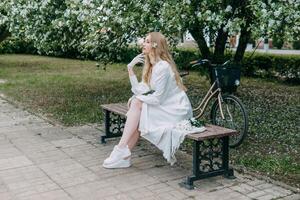 A blonde girl with long hair on a walk in a spring park. Springtime and blooming apple trees. photo