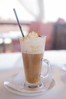 café es servido en un alto vaso vaso con un paja. el concepto de café bebidas desde el bar menú foto