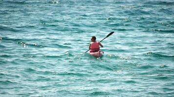 homem caiaque mar. Forte Atlético homem aprende para remo caiaque dentro aberto mar oceano em ensolarado dia. verão feriado período de férias e viagem conceito. aéreo visualizar. lento movimento video