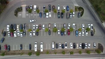 ocupado grande moderno estacionamiento con simétrico carreteras filas de estacionamiento laureles un montón de simetría y colores aéreo ver desde zumbido arriba encima mirando abajo. video