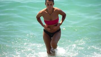 mujer, traje de baño, mar - retorciéndose fuera bikini después nadar. concepto de cuerpo imagen y aptitud física, disfrutando un sereno playa. contento mujer con Perfecto ajuste cuerpo disfruta mar playa video