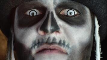 Close-up of scary man face in skull Halloween makeup of skeleton showing dirty teeth and tongue video