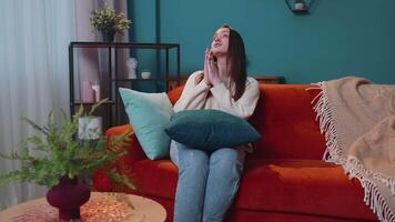 Single traurig jung Erwachsene Frau Sitzung auf Sofa beim Zuhause im Schock durch schrecklich Nachrichten beten, fragen zum Hilfe video
