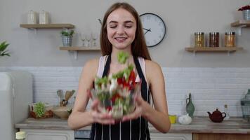 Happy young woman eating fresh raw vegetable salad posing at kitchen having positive emotion video