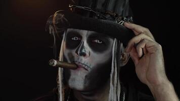 Sinister man with horrible Halloween holiday skeleton makeup raising his head and smoking cigar video