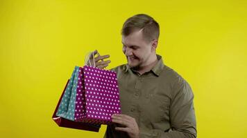 glücklich Mann zeigen Verkauf Wort Inschrift von Einkaufen Taschen, lächelnd zufrieden mit niedrig Preise video