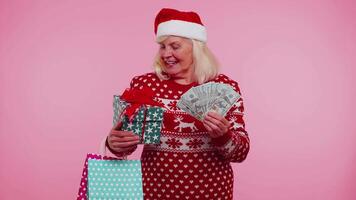 Senior grandmother woman spending money on Christmas holiday holding sale gift boxes, shopping bags video