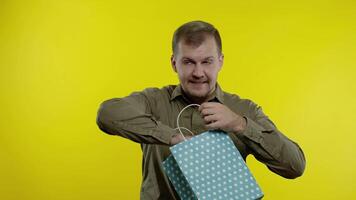 Man showing Sale word inscription from shopping bag, smiling, rejoicing discounts on Black Friday video