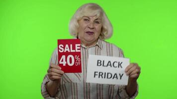 Senior grandmother showing Black Friday, 40 Percent Off discount advertisement banners. Chroma key video